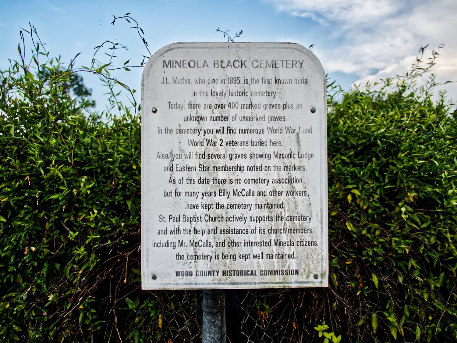 A historical marker standing just inside the fence between Cedar Memorial Gardens and the Black cemetery in Mineola reads as follows:
MINEOLA BLACK CEMETERYJ.L. Mathis, who died in 1895, is the first known burial in this lovely historic cemetery.Today, there are over 400 marked graves plus an unknown number of unmarked graves.In the cemetery you will find numerous World War 1 and World War 2 veterans buried here.Also, you will find several graves showing Masonic Lodge and Eastern Star membership noted on the markers.As of this date, there is no cemetery association but for many years Billy McCalla and other workers have kept the cemetery maintained.St. Paul Baptist Church actively supports the cemetery and with the help and assistance of its church members, including Mr. McCalla, and other interested Mineola Citizens, the cemetery is being kept well maintained.
WOOD COUNTY HISTORICAL COMMISSION